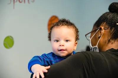 a baby looking over the shoulder of a medical provider