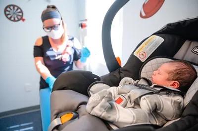 a baby in a carrier with a medical provider near them