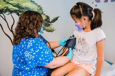 a medical provider putting a blood pressure cuff on a young girl