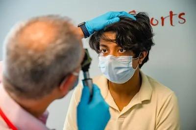 a medical provider examining the eyes of a teen boy