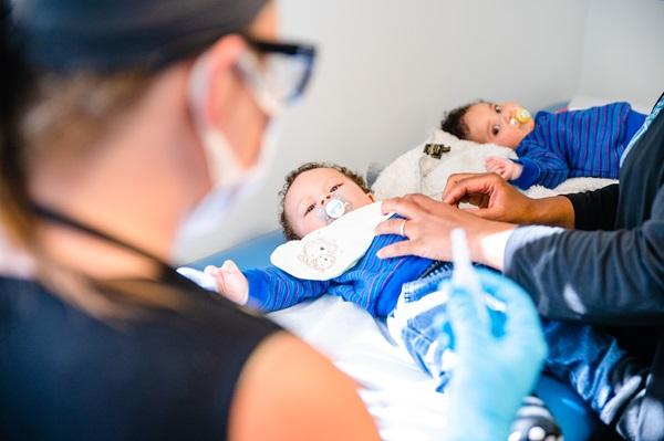 Mom watches two children on exam table